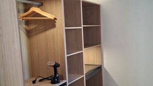 A walk-in closet with wooden shelving, a hanging rod, and a small table with a power strip. - Villa Colline St martin - Cap Agde (Agde)
