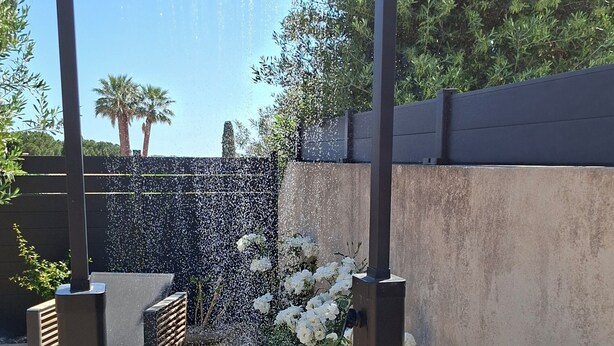 A garden with a water feature, a wooden bench, and white flowers. - Villa Colline St martin - Cap Agde (Agde)