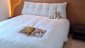 A bedroom with a bed, pillows, a bedside table, and a wall with a unique light design. - Villa Colline St martin - Cap Agde (Agde)