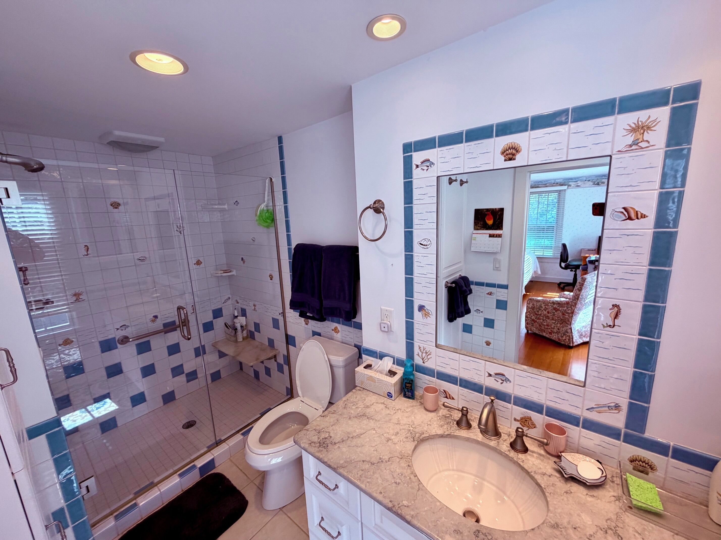 A bathroom with a shower, toilet, sink, and a large mirror.