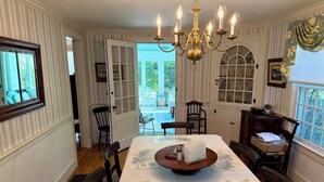 A dining room with a chandelier, floral tablecloths, and a view to the outside. - Harwich Port Walk to Beach and Village Beautiful 4 Bedroom, 3.5 Bath Home (Harwich Port)