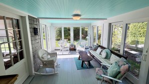 A covered porch with a rocking chair, a bench, and a sofa with cushions. - Harwich Port Walk to Beach and Village Beautiful 4 Bedroom, 3.5 Bath Home (Harwich Port)