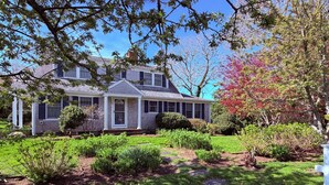A house with a front porch, a well-maintained garden, and a clear blue sky. - Harwich Port Walk to Beach and Village Beautiful 4 Bedroom, 3.5 Bath Home (Harwich Port)