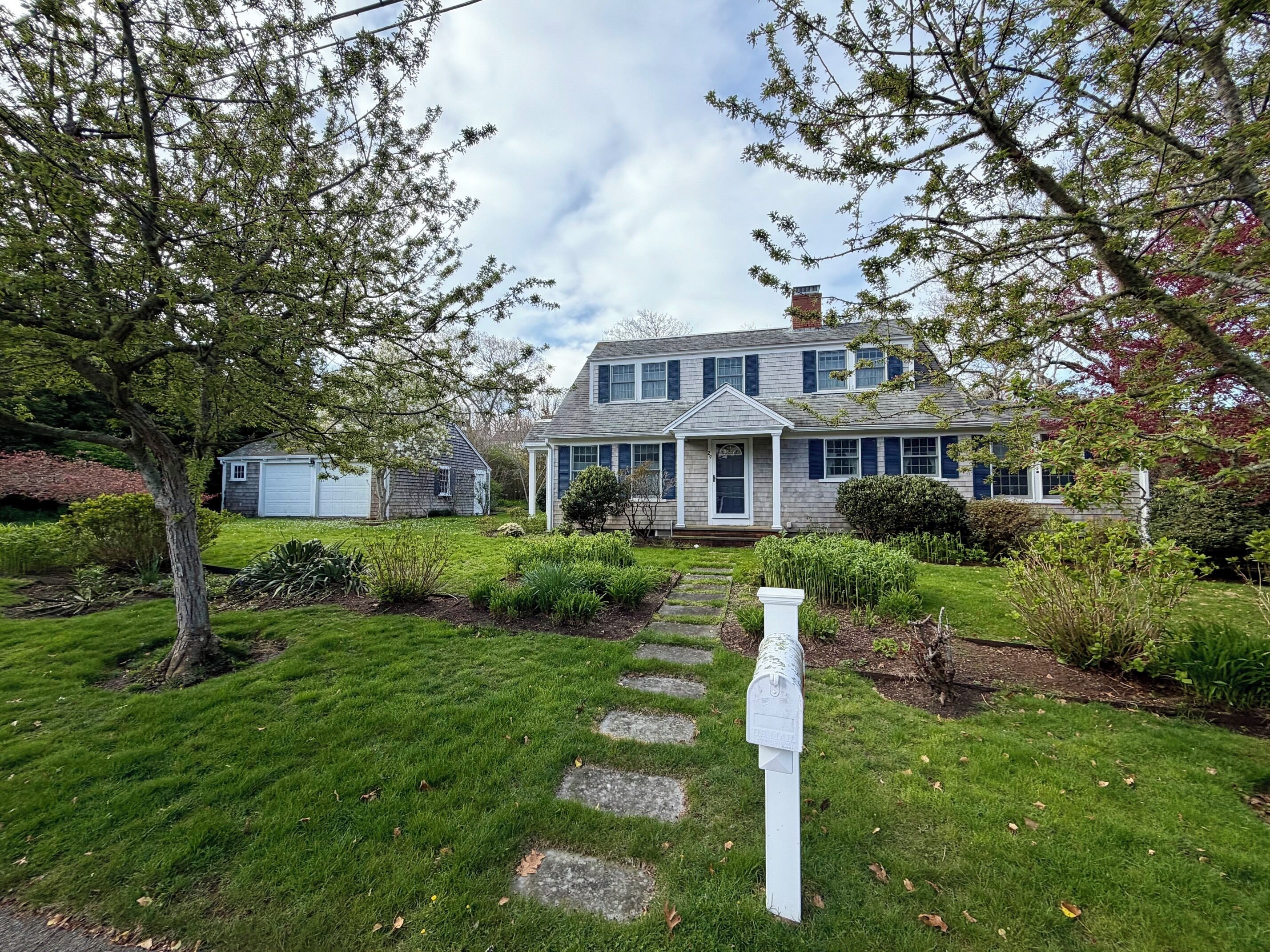 A two-story house with a front porch, a mailbox, and a well-maintained lawn.