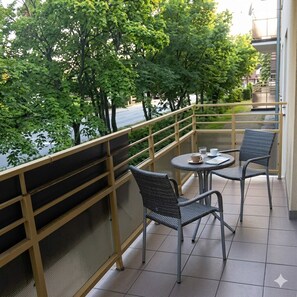 Ein Balkon mit Blick auf Bäume und ein Gebäude gegenüber.