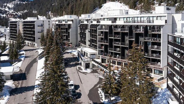 Een modern meerlaags hotel met een centrale binnenplaats, omringd door besneeuwde bergen.