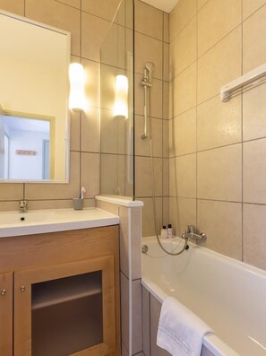 Ein Badezimmer mit Waschbecken, Spiegel, Dusche und Badewanne.