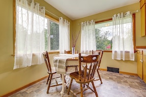 A dining area with a table set for four, wooden chairs, a vase with branches, and a window with white curtains. - Great for Families! Peaceful Snohomish Escape! (Snohomish)