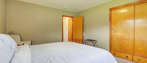 Un dormitorio con cama, armario y silla.