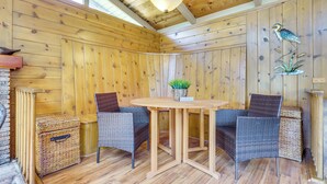 Ein Zimmer mit Holzwänden, Korbmöbeln, einem Tisch und einer hängenden Pflanze.