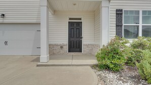 Une maison avec un porche à l’avant, une porte de garage et un petit jardin.