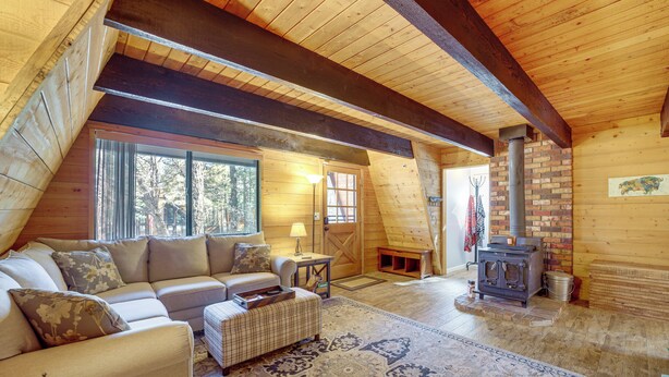 A cozy attic room with a wooden ceiling, a sofa, a patterned rug, and a wood-burning stove. - Spacious Yard & Deck! Great Space in Munds Park (Munds Park)