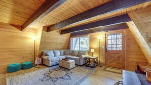 A cozy attic room with wooden walls, a sofa, ottomans, a rug, and a wooden door. - Spacious Yard & Deck! Great Space in Munds Park (Munds Park)