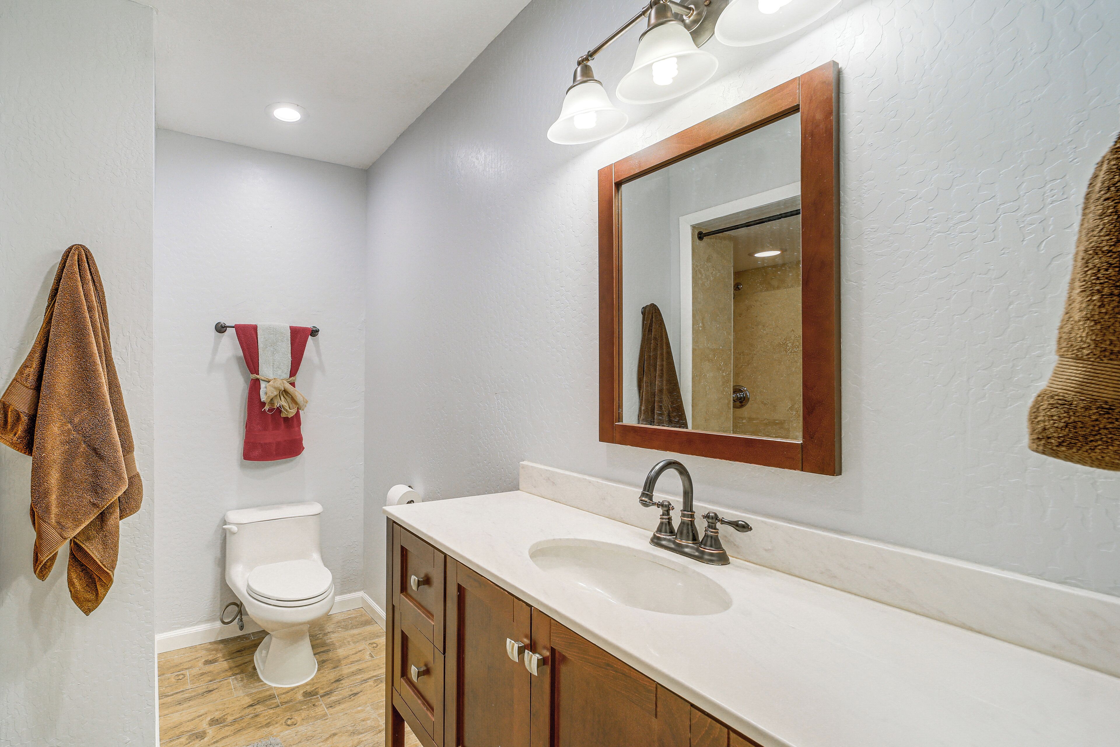 Une salle de bain avec un lavabo blanc, un meuble-lavabo en bois et un miroir avec un cadre en bois.