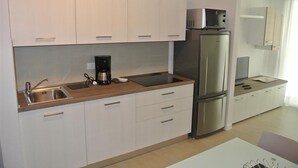 A modern kitchen with white cabinets, a stainless steel refrigerator, a coffee maker, and a sink. - Cozy Accommodation 200m From the sea (San Michele al Tagliamento)