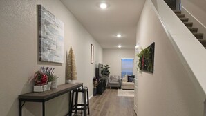 Ein Flur mit Treppe, ein Essbereich mit Tisch und Stühlen sowie ein Wohnzimmer mit Sofa.