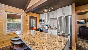 A modern kitchen with granite countertops, stainless steel appliances, and wooden cabinetry. - Sleeps 14! Hot Tub*Resort Amenities*Arcade*Games (Gatlinburg)