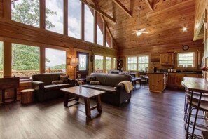 Une cabine spacieuse avec un intérieur en bois, de grandes fenêtres, un coin repas et une cuisine.