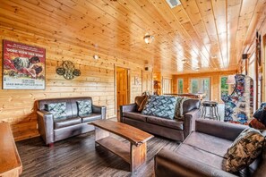 A wooden interior with leather sofas, a wooden coffee table, and a poster on the wall. - 4BR w/MTN Views! Hot Tub*Game Room*Resort*Quiet! (Gatlinburg)