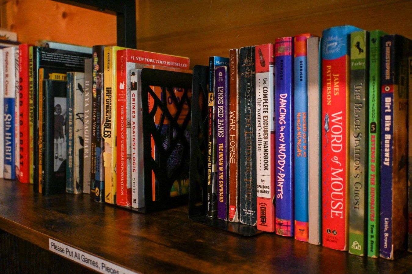 A shelf with a variety of books, including titles like 'War Horse' and 'The Lightning Thief'.