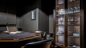A conference room with a round table, chairs, a laptop, a framed poker chart, and a cabinet with glasses and bottles. - Luxury Lakefront! 5BR*Lake Access*Hot Tub*Private! (Sevierville)