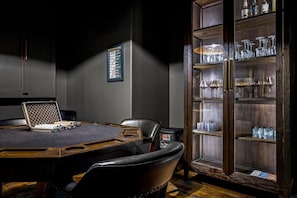 A conference room with a round table, chairs, a laptop, a framed poker chart, and a cabinet with glasses and bottles. - Luxury Lakefront! 5BR*Lake Access*Hot Tub*Private! (Sevierville)