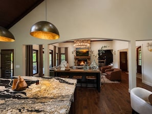 A spacious living area with a large marble island, a fireplace, and a dining area with bar stools. - Luxury Lakefront! 5BR*Lake Access*Hot Tub*Private! (Sevierville)