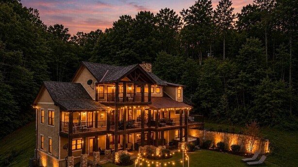A large, multi-story house with a well-lit front porch and a circular outdoor seating area. - Luxury Lakefront! 5BR*Lake Access*Hot Tub*Private! (Sevierville)