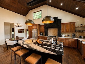 A kitchen with a large island, wooden cabinets, and pendant lighting. - Luxury Lakefront! 5BR*Lake Access*Hot Tub*Private! (Sevierville)