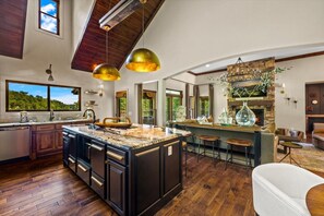 A spacious kitchen with a large island, wooden flooring, and a stone fireplace. - Luxury Lakefront! 5BR*Lake Access*Hot Tub*Private! (Sevierville)