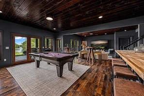A modern interior with a pool table, bar area, and a scenic view through large windows. - Luxury Lakefront! 5BR*Lake Access*Hot Tub*Private! (Sevierville)