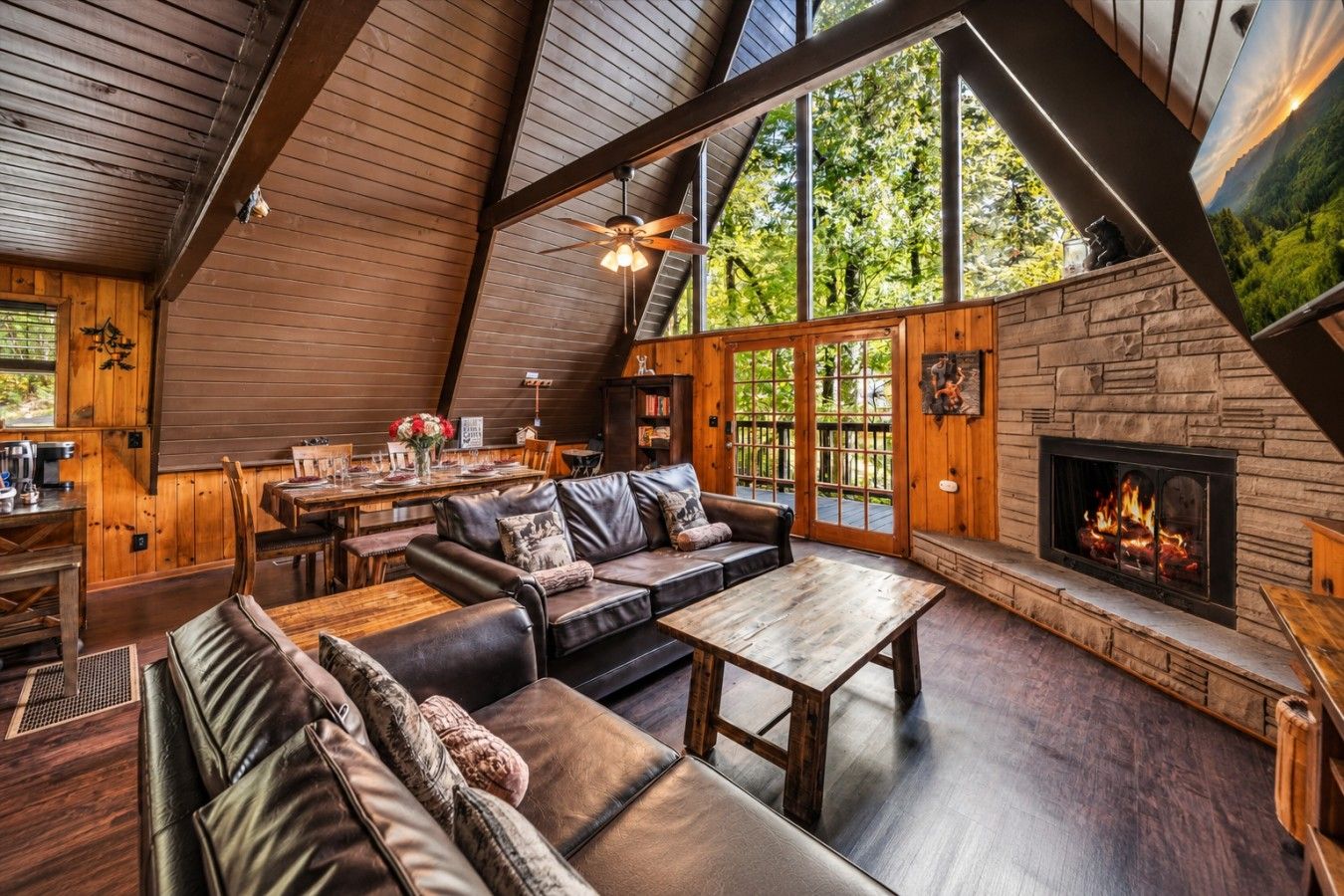 A cozy interior with a fireplace, leather sofas, and a dining area.