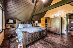 A bedroom with a wooden bed, two bedside tables, a wardrobe, and a door leading to another room. - Peaceful 4BR w/Hot Tub*Theater*Views*Resort Access (Gatlinburg)