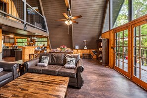 A spacious interior with a high ceiling, a dining area, and a view through large windows. - Peaceful 4BR w/Hot Tub*Theater*Views*Resort Access (Gatlinburg)