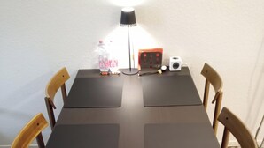 Ett rektangulärt bord med fyra stolar, en lampa och några föremål på bordet.
