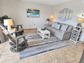 Ein Wohnzimmer mit einer Couch, Sesseln, einem Couchtisch, einem Teppich und Wandbildern.