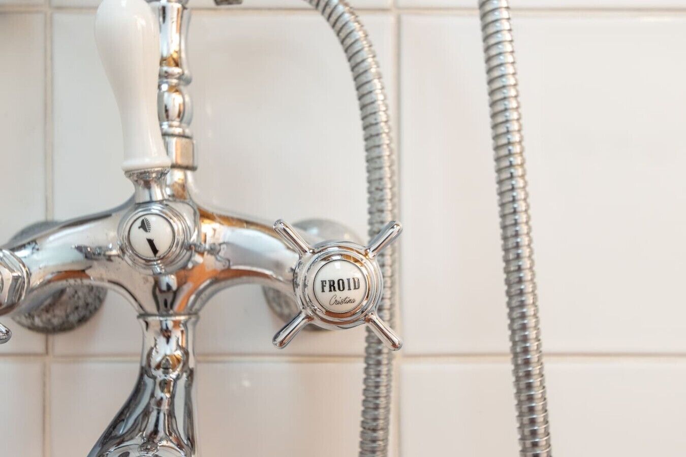 Un rubinetto da bagno con l'etichetta 'FROHD' e un tubo flessibile per la doccia.