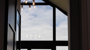 A room with large windows, a sloped ceiling, and a hanging light fixture. - House Sleeps 10 With Enclosed Garden (Reading)