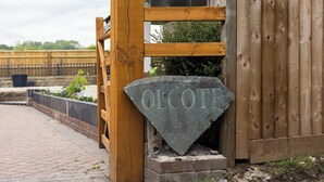 A wooden gate with a stone sign reading 'OLCOTE' in front of a building. - House Sleeps 10 With Enclosed Garden (Reading)