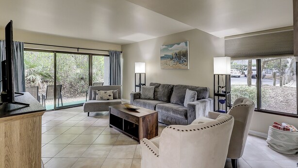 A spacious living room with a sofa, armchairs, a coffee table, and a television. - Sunset Rentals | Treetops 6101 | Dog Friendly (Hilton Head Island)