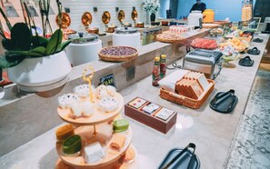 Buffet com diversos alimentos, incluindo pão, frutas e acompanhamentos.