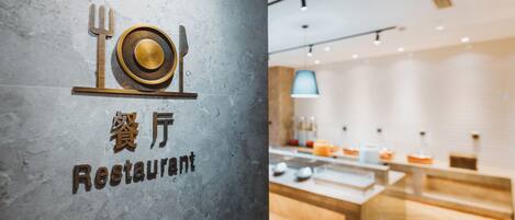 A restaurant sign with a table and utensils, and a modern interior with a counter and pendant lighting.