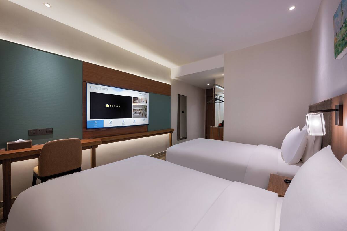 A hotel room with two beds, a desk, a flat-screen TV, and a modern design.