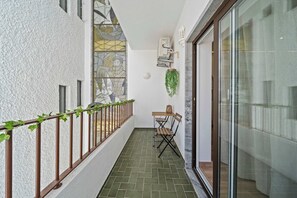 A narrow balcony with a tiled floor, a metal railing, a small table with a chair, and a hanging plant. - Stylish & Sleek Flat near the Beach by HostWise (Armação de Pêra)