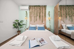 Quarto com cama, duas mesas de cabeceira, uma planta em vaso e um espelho.