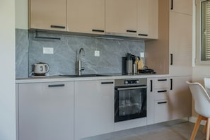 A modern kitchen with a built-in oven, a stainless steel sink, and a coffee maker.