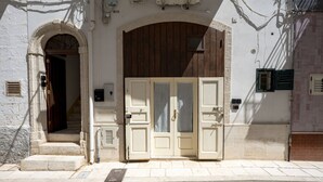 Une entrée d’immeuble avec une grande porte en bois, un arc en pierre et une petite fenêtre.