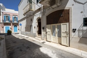 Una calle estrecha con edificios, una puerta azul y una puerta blanca.
