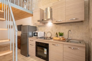 A modern kitchen with stainless steel appliances, a built-in oven, and a wooden countertop.