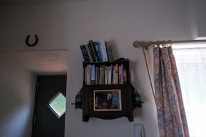 Une bibliothèque remplie de livres, une porte avec une fenêtre et un rideau.